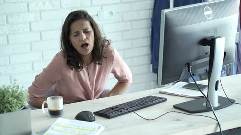 Businesswoman having stomach pain while working on PC computer in office  
