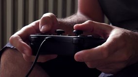 Man playing video game with joypad, close up of male hands with gaming equipment