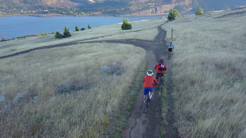 Mountain bikers riding a cliff-side trail in Washington on the Columbia River overlooking Oregon.