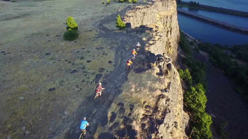 Mountain bikers riding a cliff-side trail in Washington on the Columbia River overlooking Oregon.
