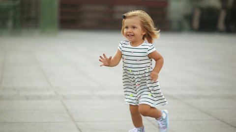 Little Blonde Girl in Dress and Blue Sneakers is Running to Her Mother Wearing Red Shoes. View of the Foots.