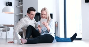 Beautiful couple using digital tablet talking and smiling while sitting on the floor near fireplace