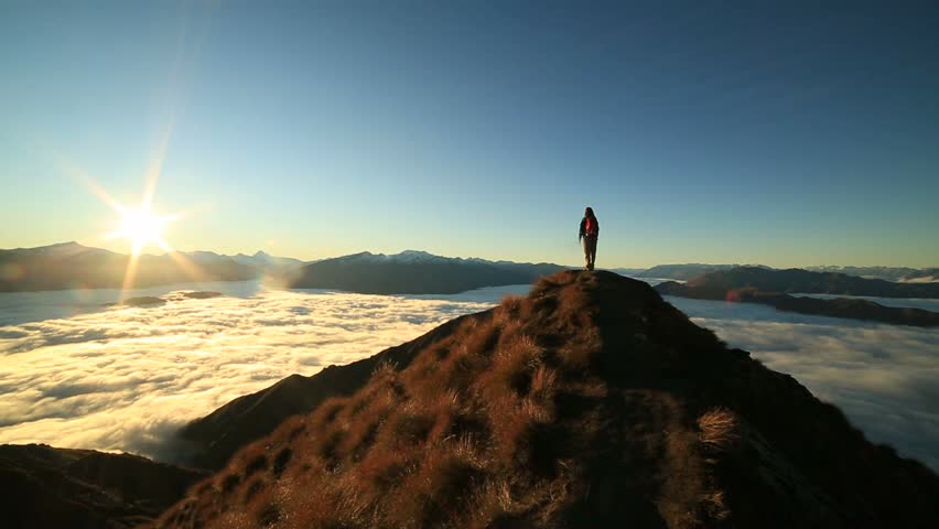 Young woman hiker stands alone on mountain summit above the clouds at sunset, arms outstretched as a sign of achievement and success.
Standing on top of the world, individuality on a mountain top  Royalty-Free Stock Footage #30393364