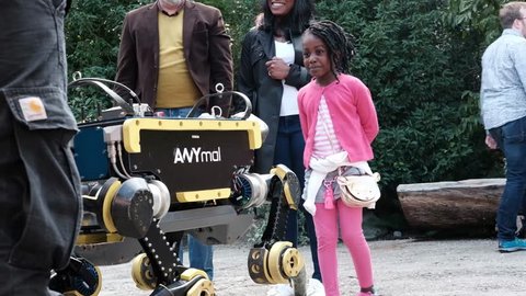 Zürich, Switzerland – 03 September 2017: Kids playing with robot during a robotic demo held by the RSL, ETH Zurich, at the Zoo. They play with the quadruped robot and imitate his movements. 