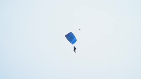 A man is flying on a blue parachute landing, a view from the crowd