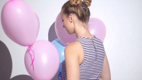 Beauty girl with colorful air balloons spinning and laughing, on white background. Beautiful Happy Young woman on birthday holiday party. Joyful model having fun, celebrating. 4K slow motion video