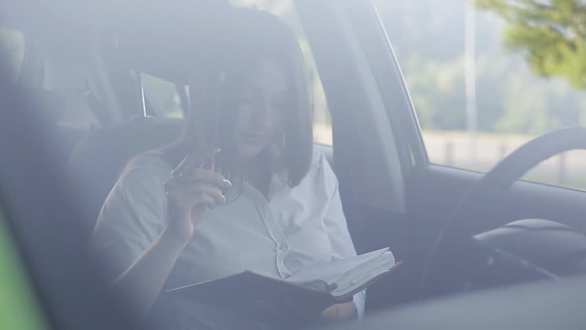 The girl driver communicates by phone in the parking lot and makes notes in her diary | Shutterstock HD Video #30404896
