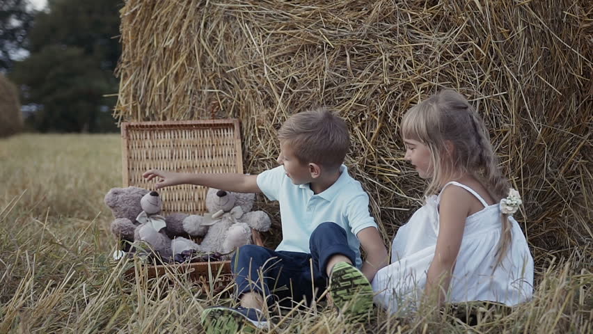 The boy and the girl are playing fun soft toy bears. A girl in a white dress. Sunset slow motion