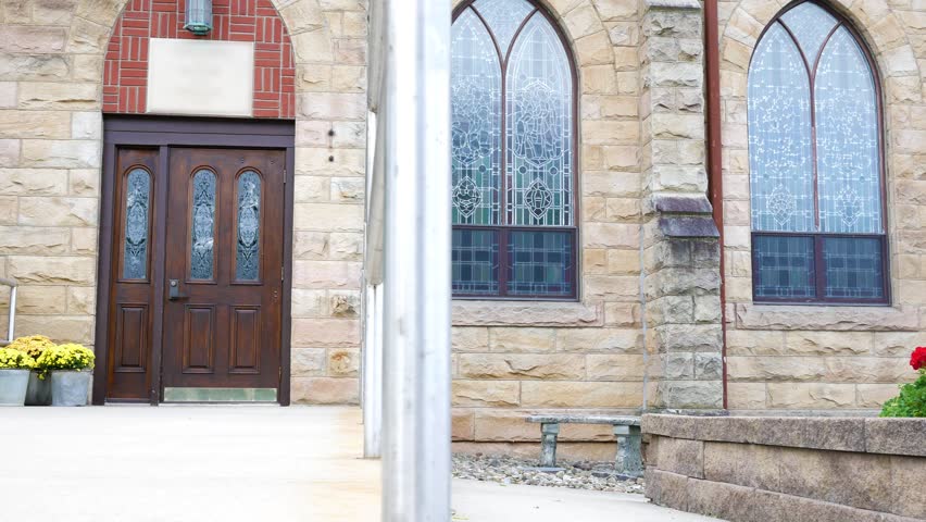 Camera pans across the entrance of a church or chapel exterior in summer