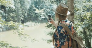 Young woman taking a photo on a smartphone in a forest. Beautiful caucasian girl spending time in a moutain woods.