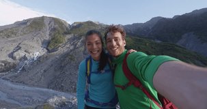 Happy lifestyle couple selfie video. New Zealand tourists smiling happy in nature by Franz Josef Glacier, Westland Tai Poutini National Park, South Island, New Zealand. Couple having fun on travel.