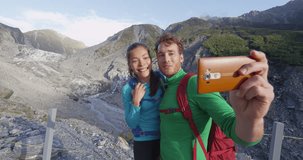 Couple taking phone selfie. New Zealand tourists smiling happy in nature by Franz Josef Glacier, Westland Tai Poutini National Park, South Island, New Zealand. Couple having fun on travel. SLOW MOTION
