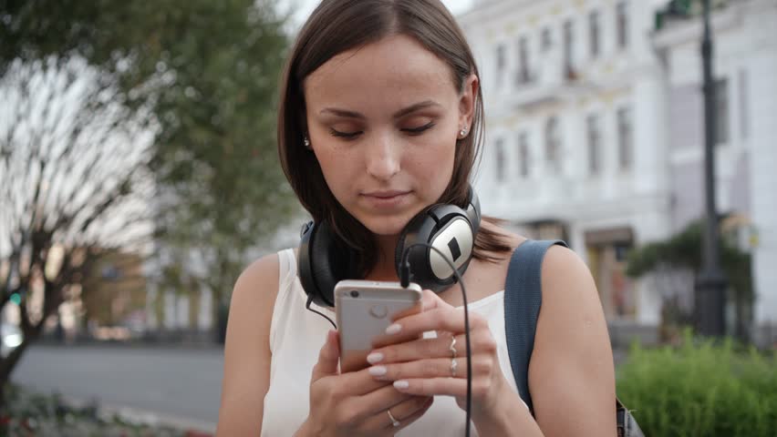 Young woman with smartphone and headphones listening to music on city street. Royalty-Free Stock Footage #30419539