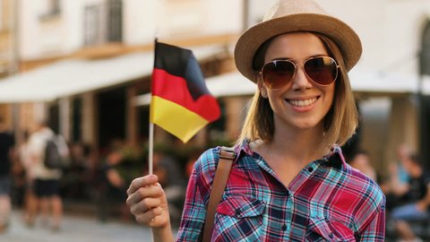 Happy attractive woman with germany flag posing on camera and smiling on the city street background. close up