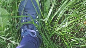Female feet in sneakers walks on the green grass in slow motion. 1920x1080
