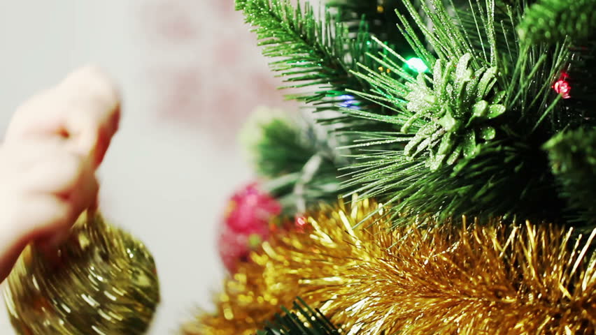 child decorates a Christmas tree closeup