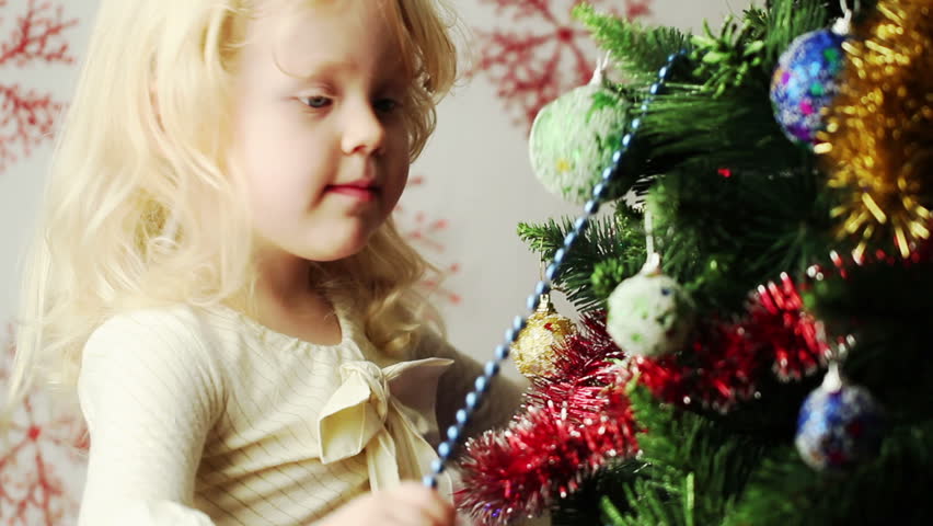 beautiful little blonde girl decorates the Christmas tree