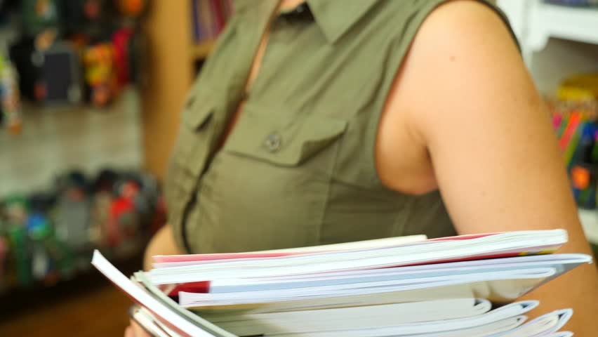 Portrait of a woman standing in library. Bookcase bookshelves in background. 4k, slow-motion
