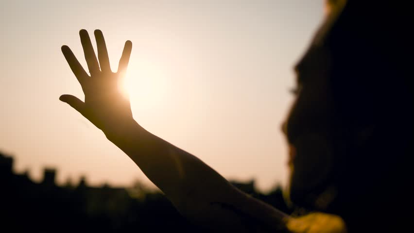 Thoughtful young woman is trying to close the sun by hand in summer evening, silhouette of face and hand | Shutterstock HD Video #30439879