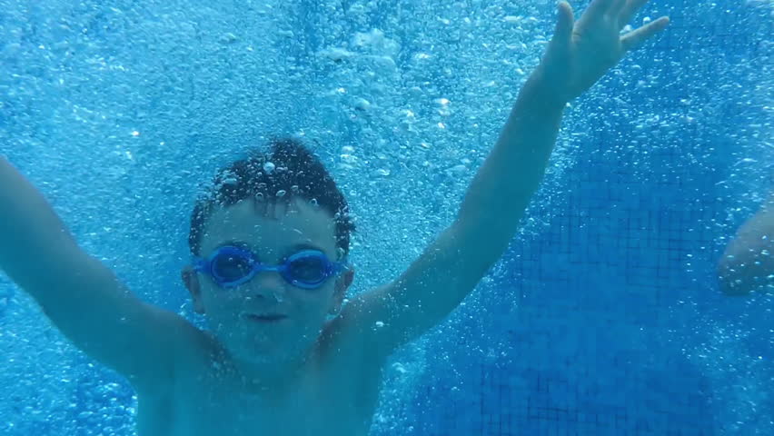 Slow motion underwater jump into a swimming pool. Children having fun in the water and learning to swim