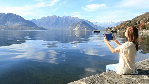 Young woman using digital tablet by the lake 
People travel concept
