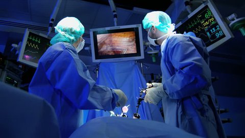 Medical Caucasian, European surgical team in scrubs performing laparoscopic surgery on the patient in operating theater using video camera technology RED WEAPON