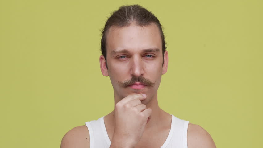 Closeup brooding man in shirt touching his chin over yellow background. Concept of emotions | Shutterstock HD Video #30452566