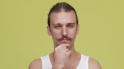 closeup brooding man in shirt touching his chin over yellow background. Concept of emotions