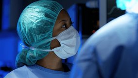 Laparoscopy surgical operation transmitted on hospital monitors performed by multi ethnic female and male Caucasian training as surgeons wearing surgical mesh and scrubs RED DRAGON