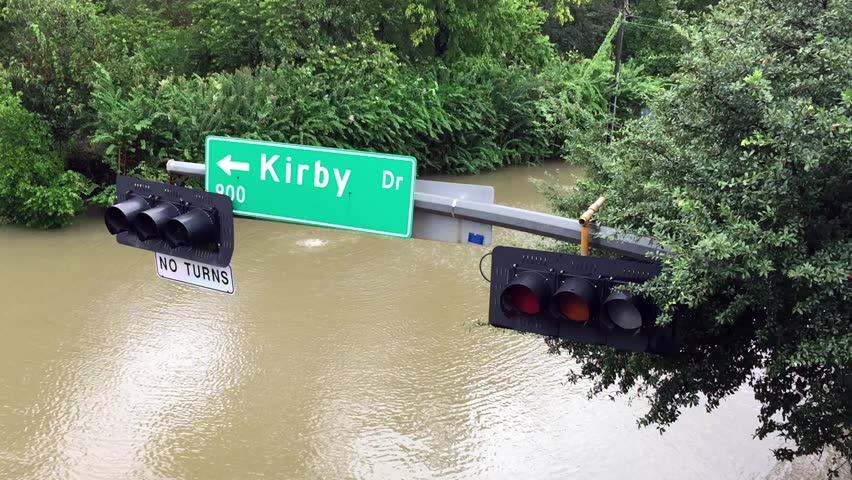 A street sign hanging over a flooded street after Hurricane Harvey came through town.