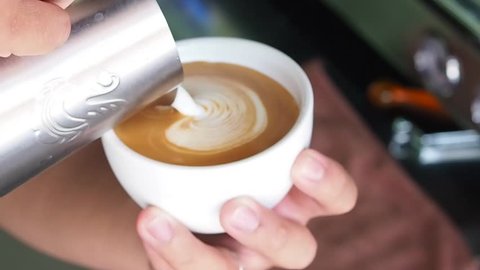Barista pouring milk for making latte art.