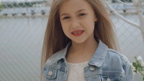 Smart little female model with long hair smiling and looking at camera 4K