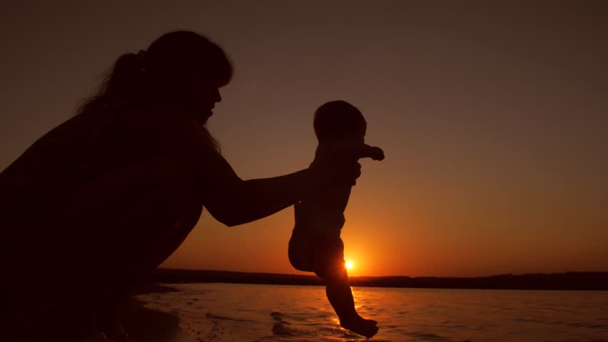 Baby washes his feet in water in hands of his beloved mother at evening sunset red sun. | Shutterstock HD Video #30468472