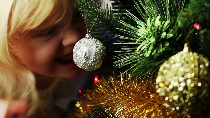beautiful little blonde girl decorates the Christmas tree
