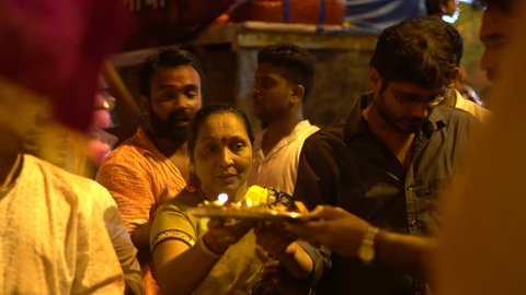 A group of people are seen performing a prayer to an idol of lord Ganesh, celebrating the last day of Ganesh Chaturthi festival in Kandivali, Mumbai, Maharashtra, India. Shot in September 2017.