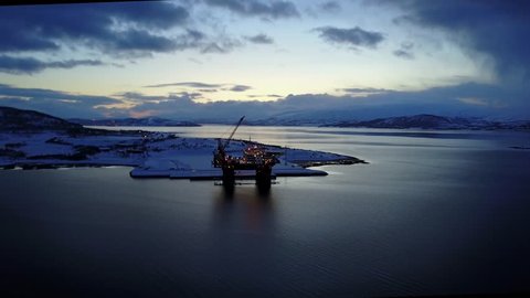 Aerial of arctic commercial oil drilling platform docked at sunset