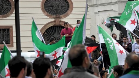 Slow Motion Pan shot of protestors waving Syrian national flag at demonstration in Frankfurt Germany