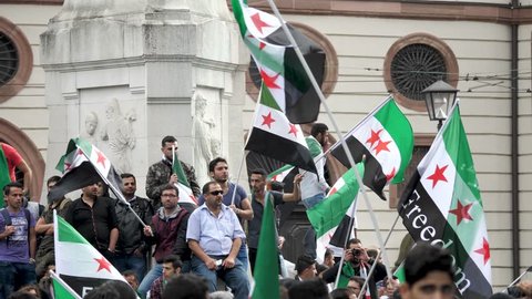 Slow Motion Pan shot of protestors waving Syrian national flag at demonstration in Frankfurt Germany