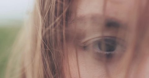 Close Up of Woman Eyes Covered with Hair Blowing on the Wind. SLOW MOTION 4K DCi. Green Eyes. Determined Female Sight. Stormy weather, autumn, winter, spring.
