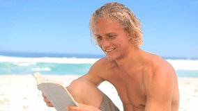 Smiling blonde man reading a novel on the beach - Powered by Shutterstock - Get 15% off with code: PIKWIZARD15