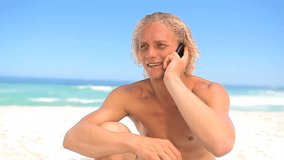 Happy blonde man talking on the phone on the beach - Powered by Shutterstock - Get 15% off with code: PIKWIZARD15