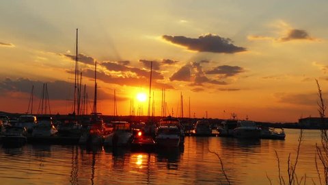 Evening marina port in Sozopol, Bulgaria. Yachts and ships against backdrop of sunset.
