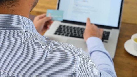 Businessman using laptop computer typing personal identity information while shopping digitally online and paying with credit card