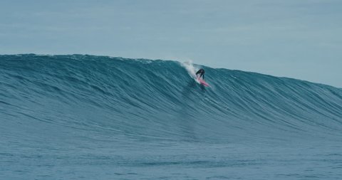 Surfer rides giant blue ocean wave. Shot on RED in 4k. Big wave surfing. 