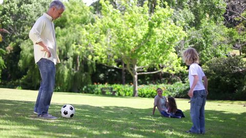 Father playing football with his children in a park