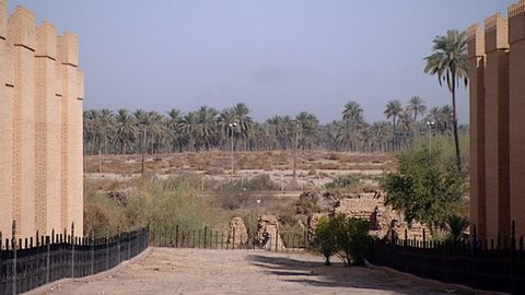 HILLAH, IRAQ - CIRCA 2002: Zoom-out from a paved road to show the mud brick crenelated walls of ancient Babylon. Since the Gulf War occupying forces have caused irreparable damage to the site.