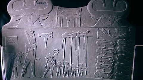 CAIRO, EGYPT - CIRCA 2002: Tilt-down from two human-faced bovine heads of a cow goddess, flanking a serekh to two men lassoing confronting serpopards. Narmer Palette, Museum of Cairo.