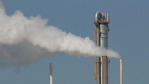 Close up of pure white steam or smoke billowing out of an industrial chimney on a refinery in Spain