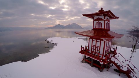 Epic 4k Aerial of Japanese Temple in Winter over lake with crazy reflections during sunset 스톡 비디오
