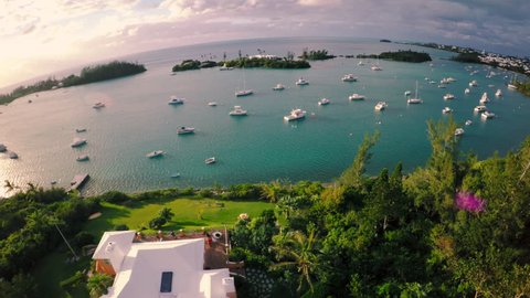 Tropical Sunset Aerial Shot of Golden Light Over Crystal Clear Waters with Sailing and Fishing Boats with Green Grass and White Houses in Bermuda